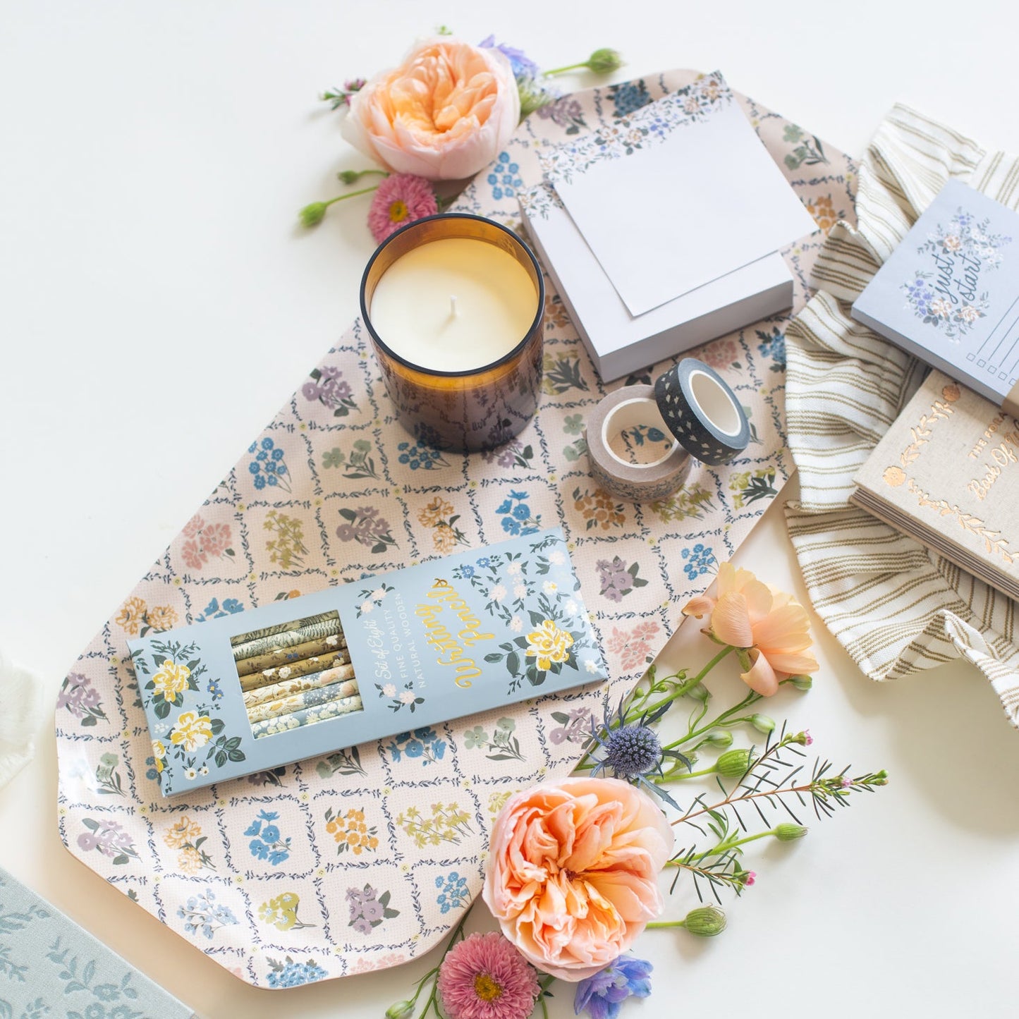 This stationery collection by Bonnie Christine includes the Blossom Mini Note Block, Blossom Small Notepad, Blossom Large Notepad, Blossom List, Pipet Pencil Set, Masking Tape-washi tape, Daydreamer Sketchbook, Signature Soy Candle, and Trellis Serving Tray all adorned with delicate floral designs, perfect for adding beauty to everyday planning, note-taking, and list-making.