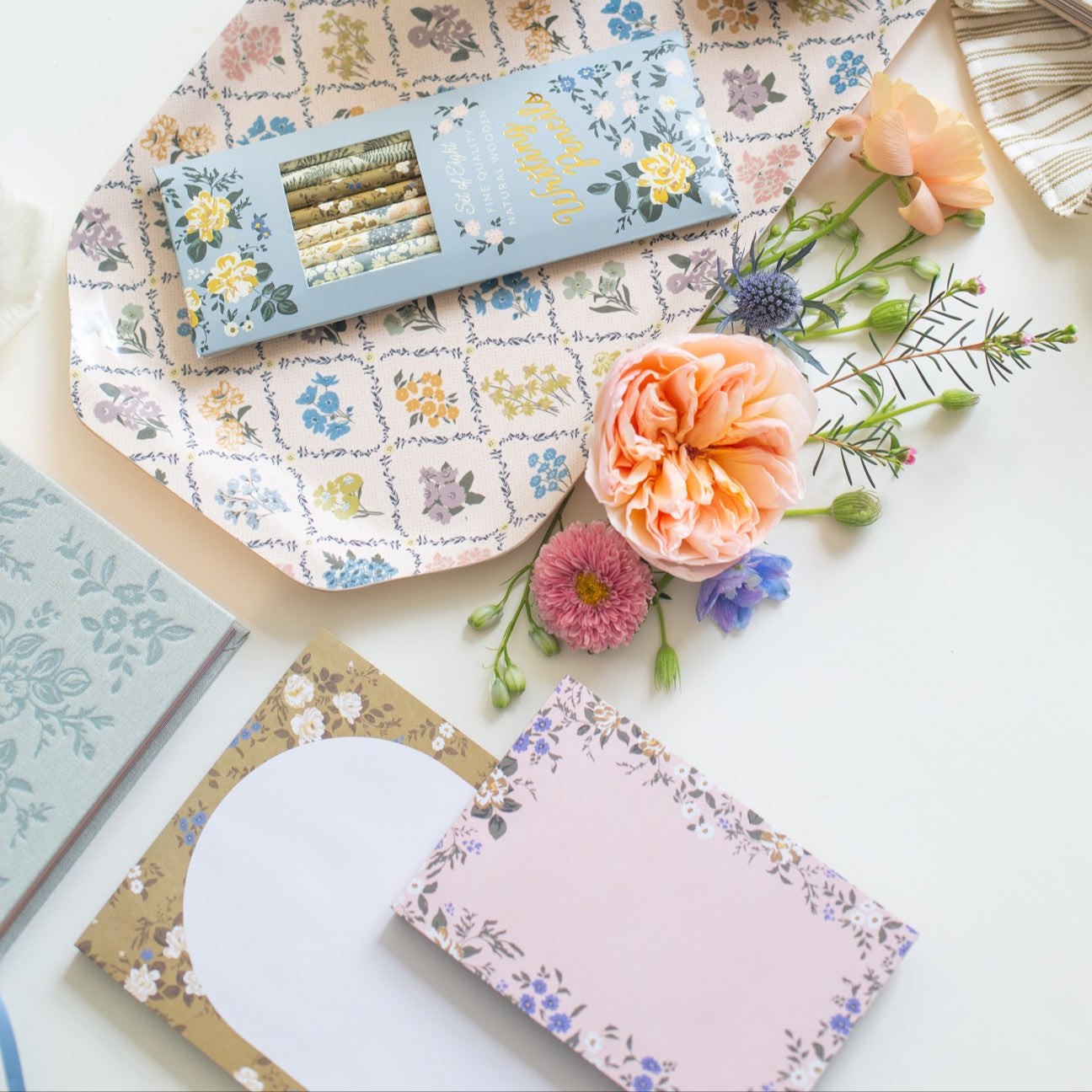 This stationery collection by Bonnie Christine includes the Blossom Mini Note Block, Blossom Small Notepad, Blossom Large Notepad, Blossom List, Pipet Pencil Set, Masking Tape-washi tape, Daydreamer Sketchbook, Signature Soy Candle, and Trellis Serving Tray all adorned with delicate floral designs, perfect for adding beauty to everyday planning, note-taking, and list-making.