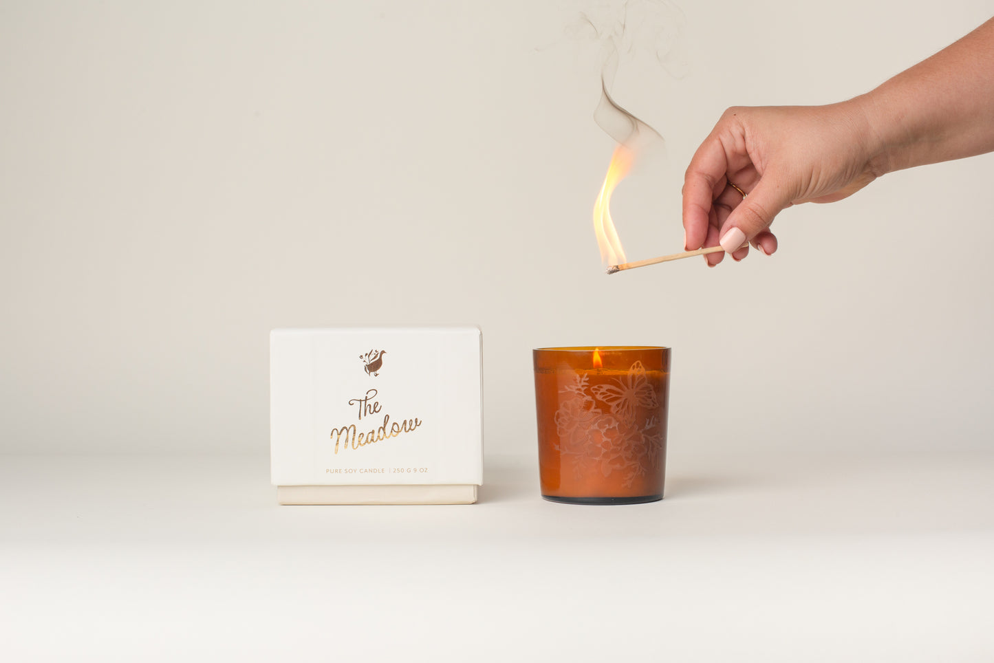 This Meadow Signature Candle by Bonnie Christine, with its etched floral amber glass vessel and handmade box, adds a warm, inviting touch to home decor, making it the perfect gift or housewarming present for those who love cozy, artful spaces.